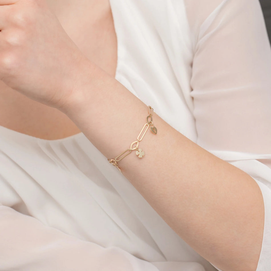 Zlatý náramok so širokými článkami a príveskami zámok a štvorlístok